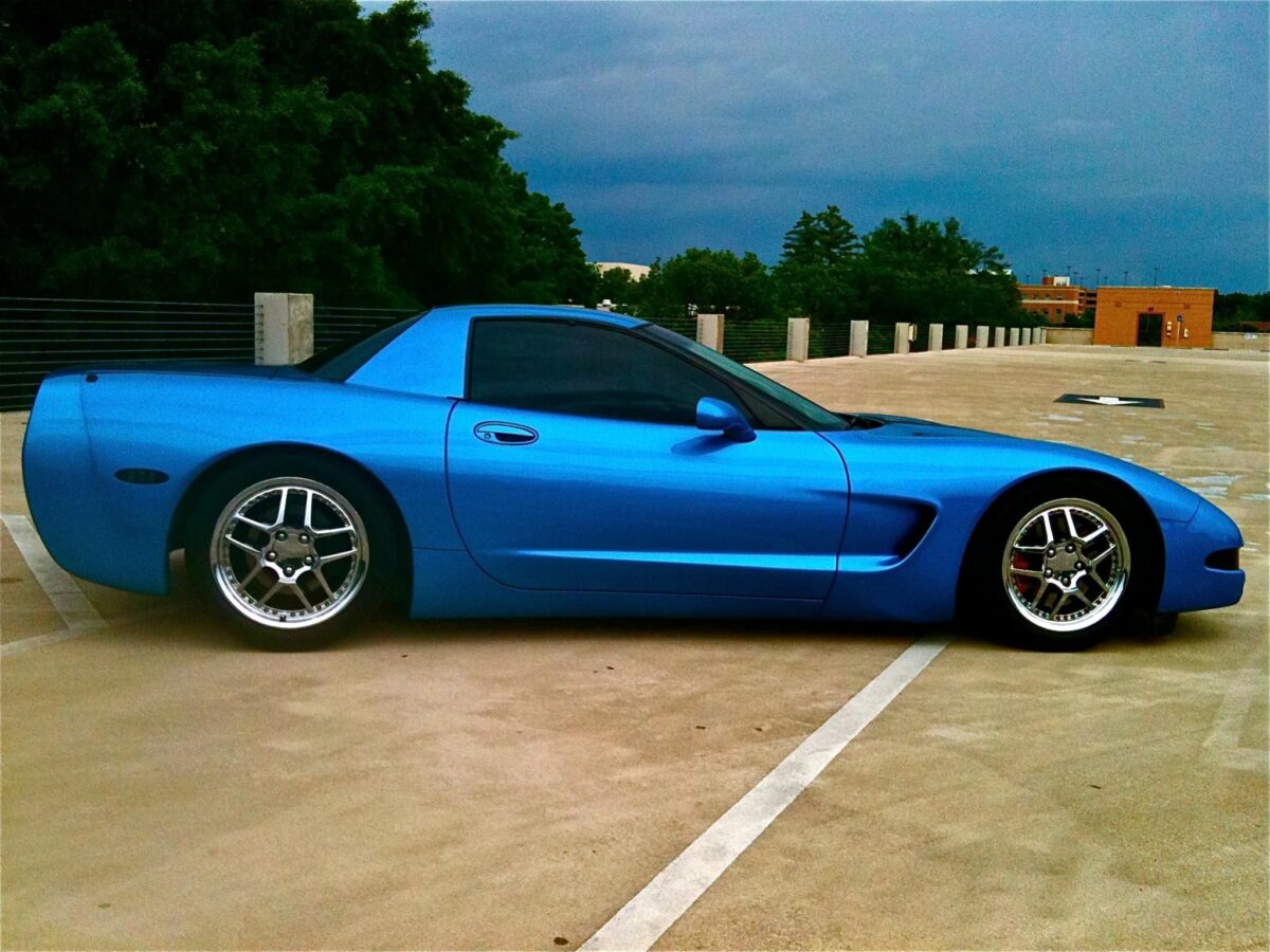 A Nassau Blue Corvette in a parking lot on a grey day still looks vibrant as ever.