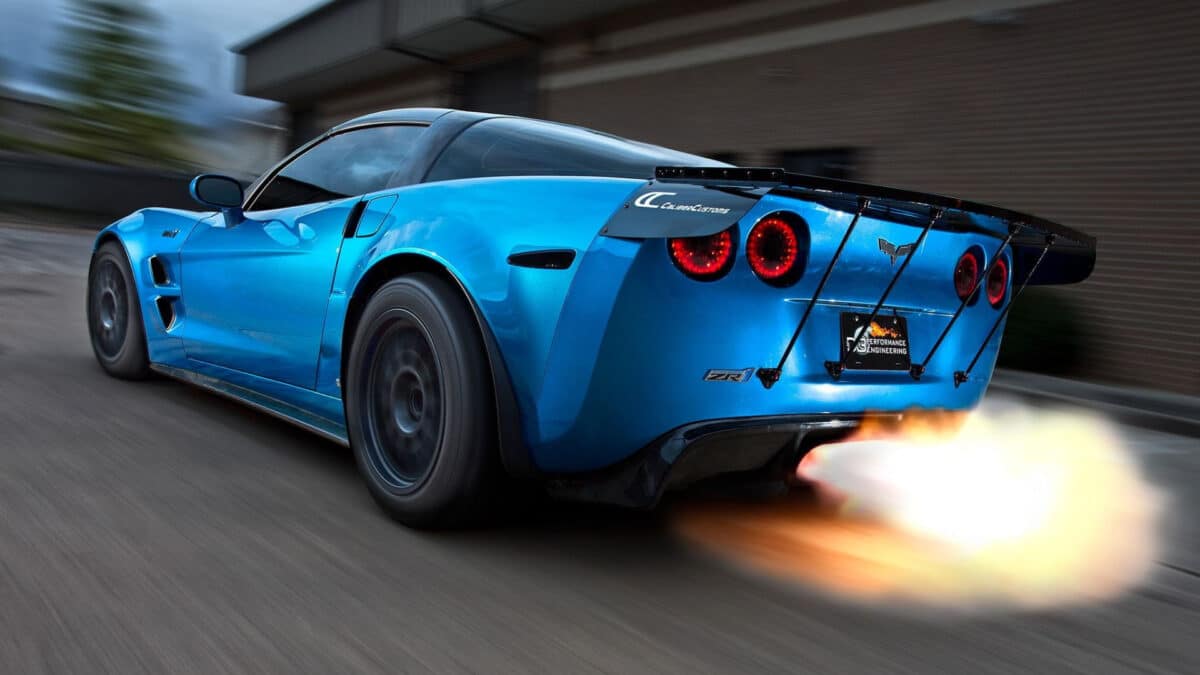 A blue Corvette with backfire speeds dwn a road.