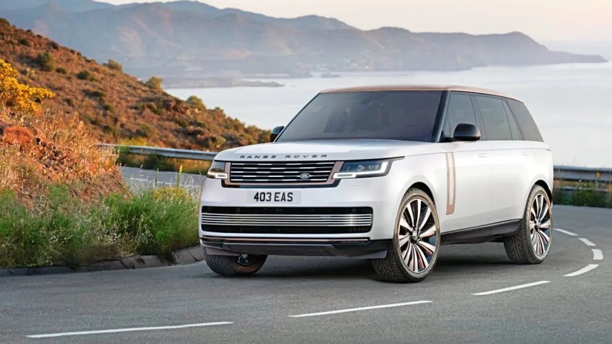 The AWD white range rover drives in a seaside country road along rolling hills.