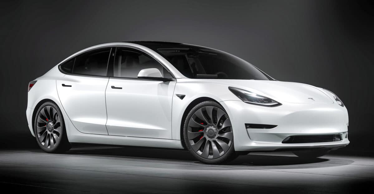 a white tesla with a dark background is in a spotlight