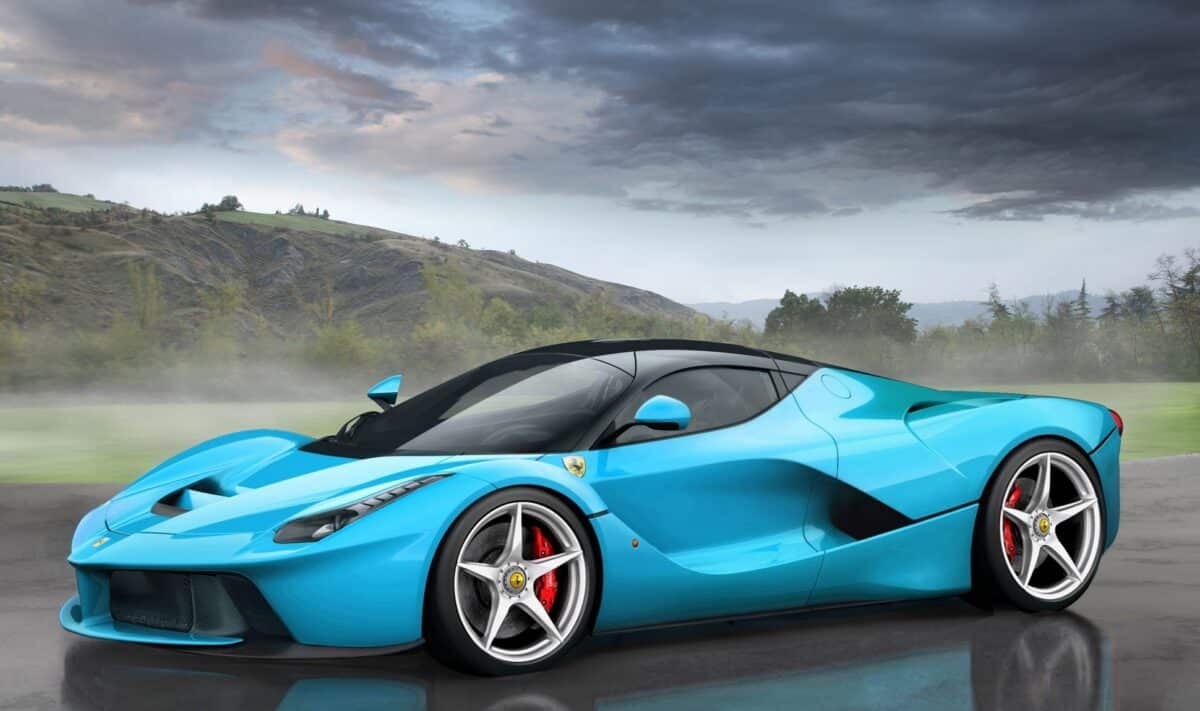 A blue Ferrari is outside on a foggy road.