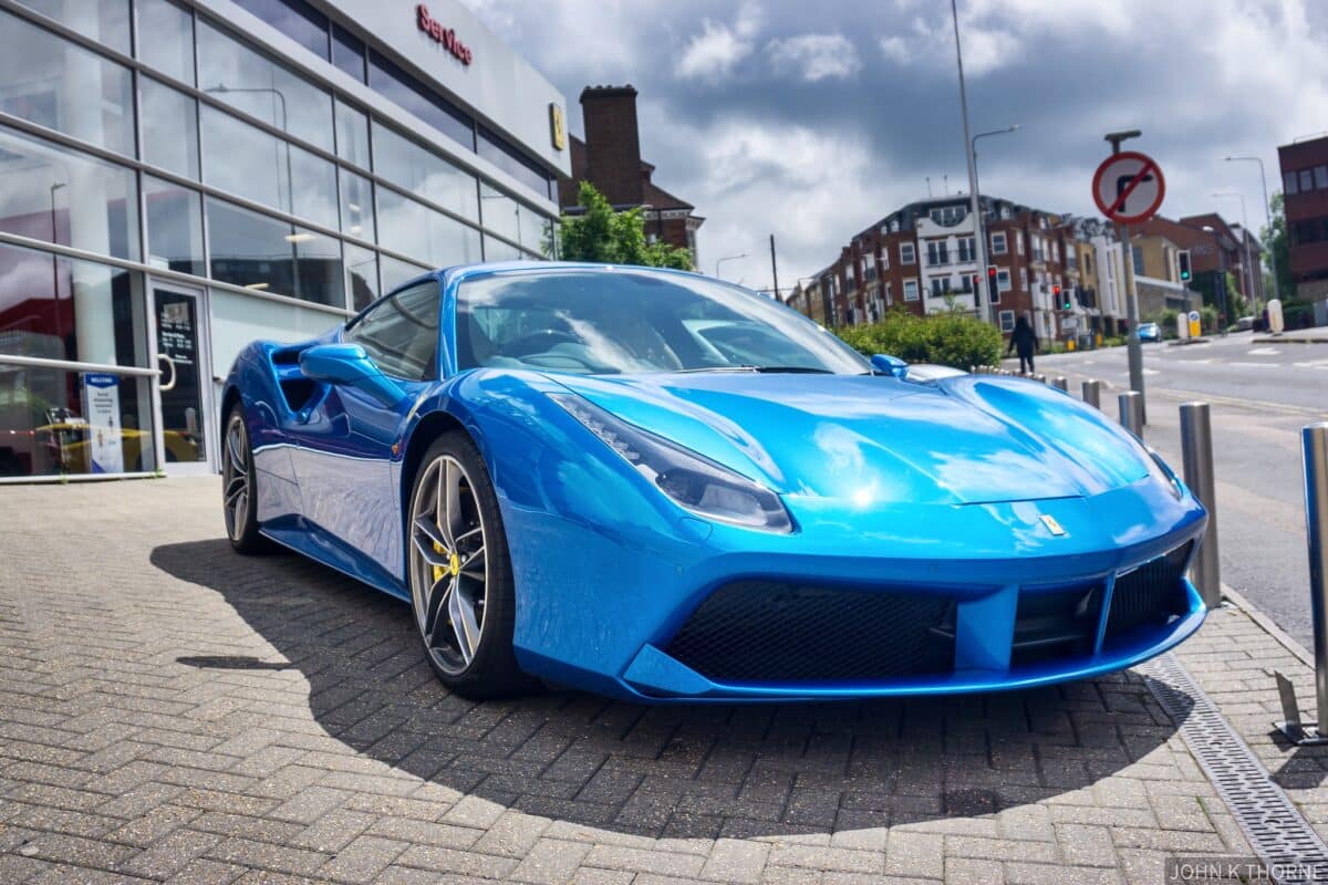 a blue ferrari is parked on a the pavement in europe. 