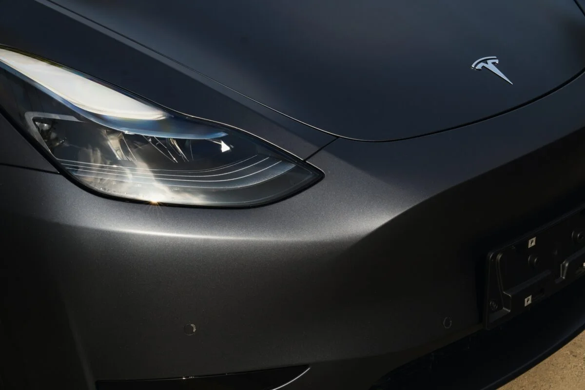 A black Tesla Stealth PPF Model Y, close up near the right headlight.