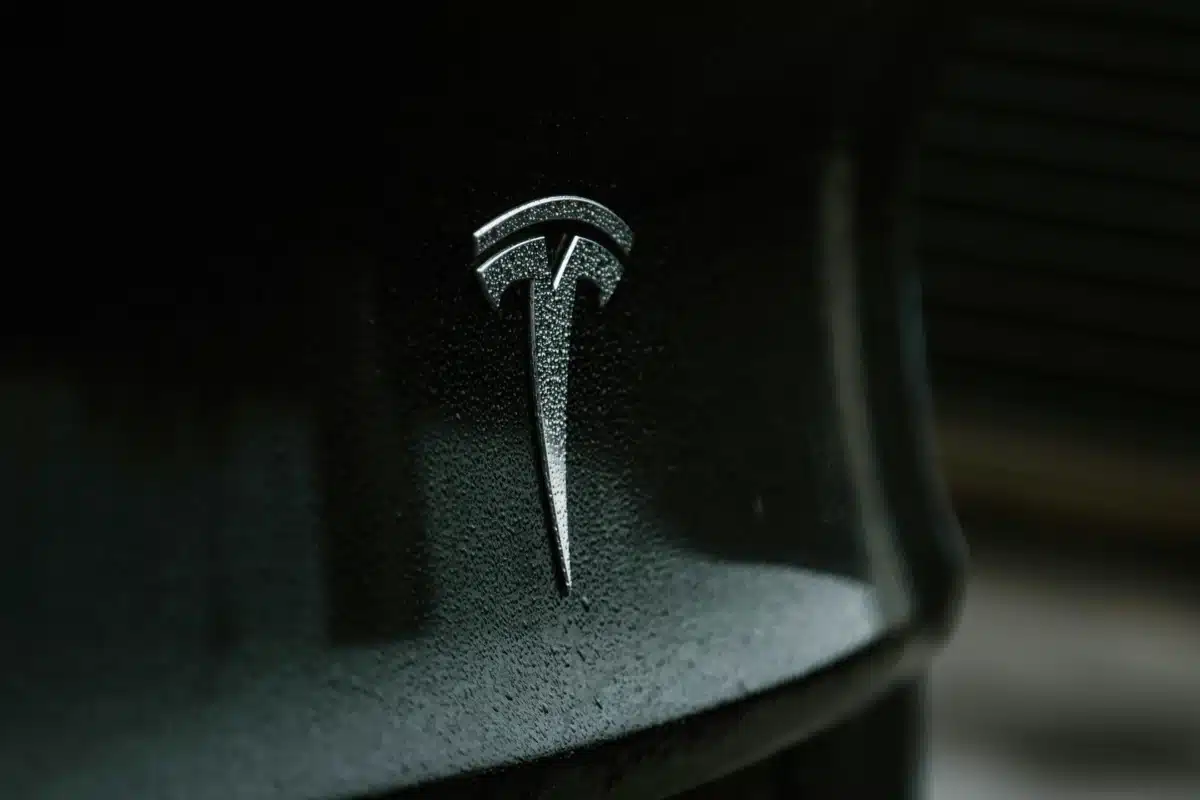 A close up of a Tesla emblem on a black matte Tesla. It's shining after getting Tesla detailing done.