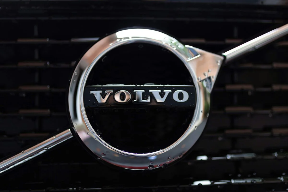 The classic Volvo logo on the front grill of a car is close up.