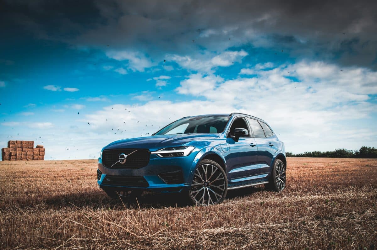 A blue luxury Volvo car is parked in some field on a sunny day. Is Volvo a luxury car?
