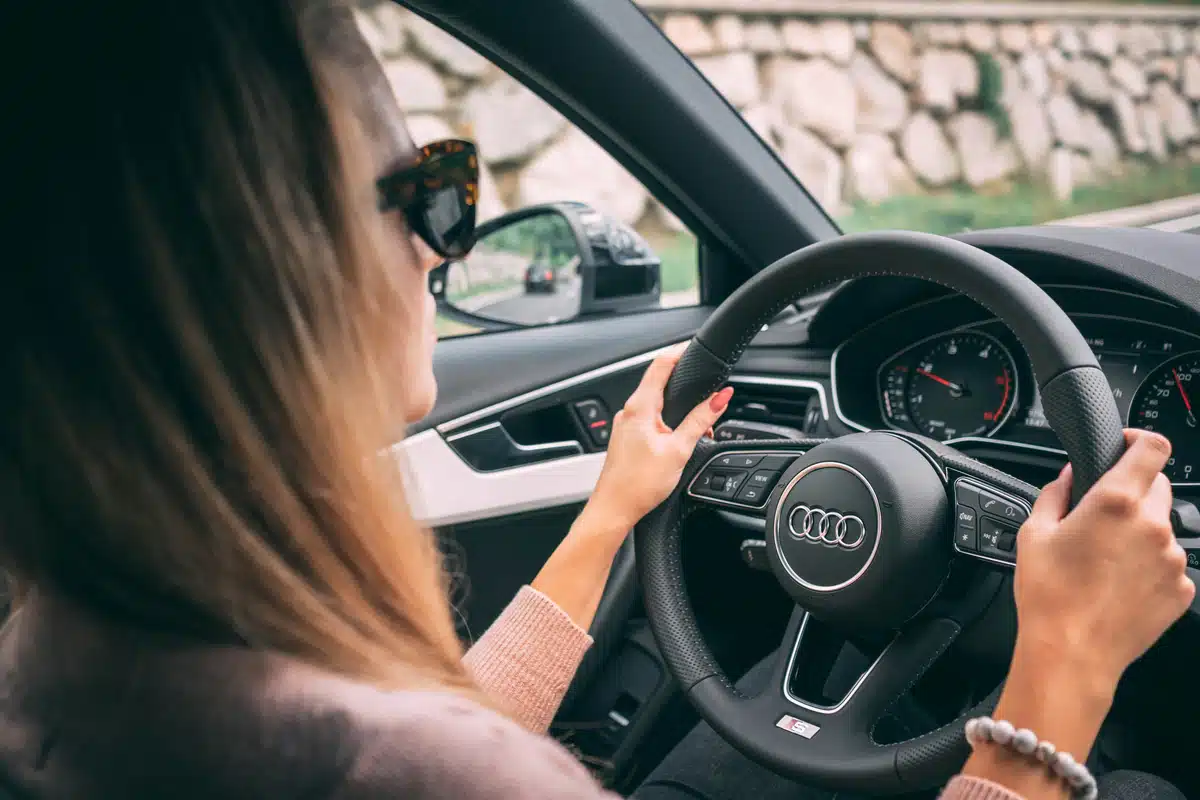 An over the shoulder view of a woman driving an Audi A4, one of the safest luxury cars of 2023.