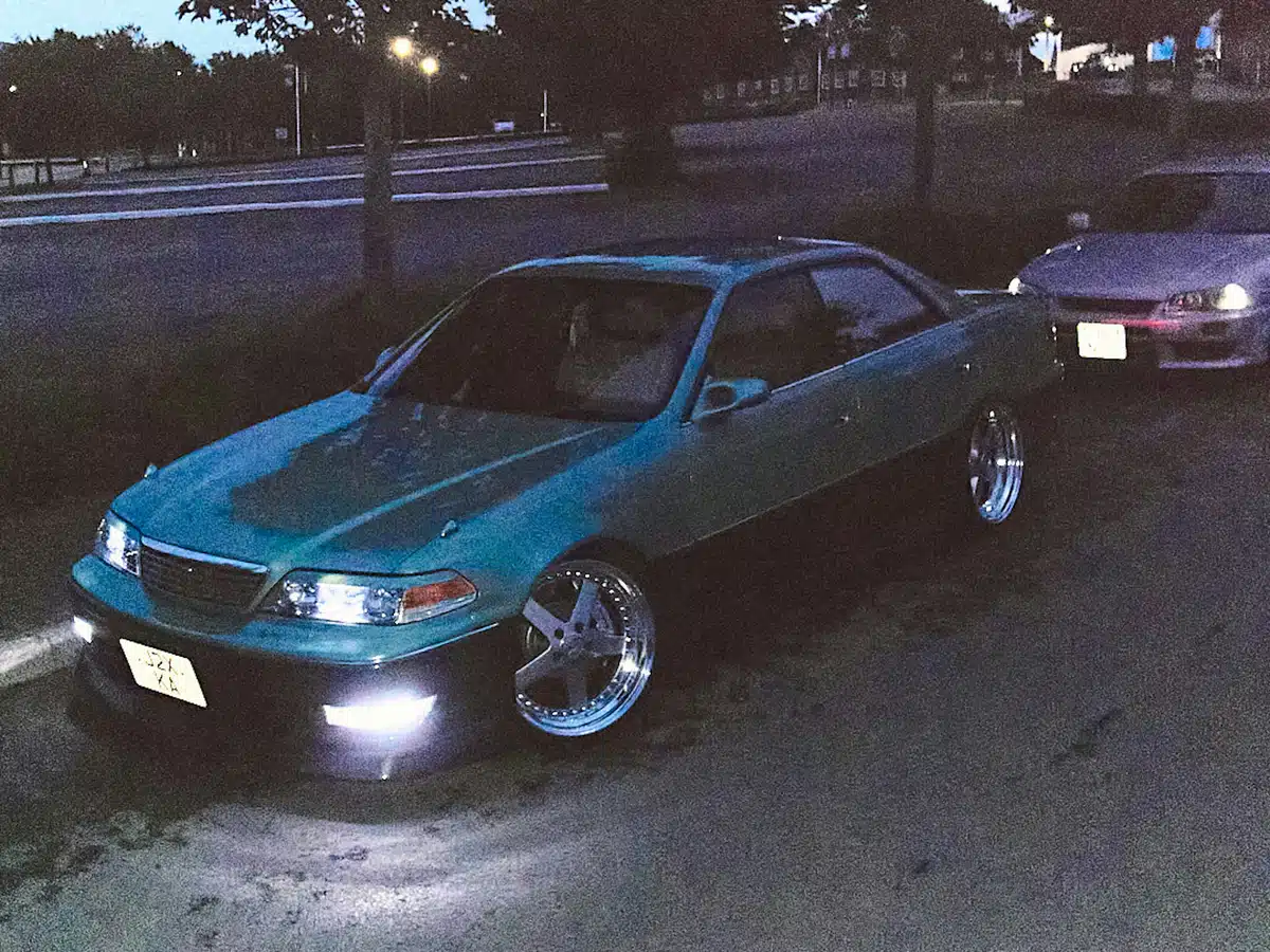 Shot in film during dusk, two JDM cars are parked on the side of a road with their headlights on. This is the ultimate JDM aesthetic.