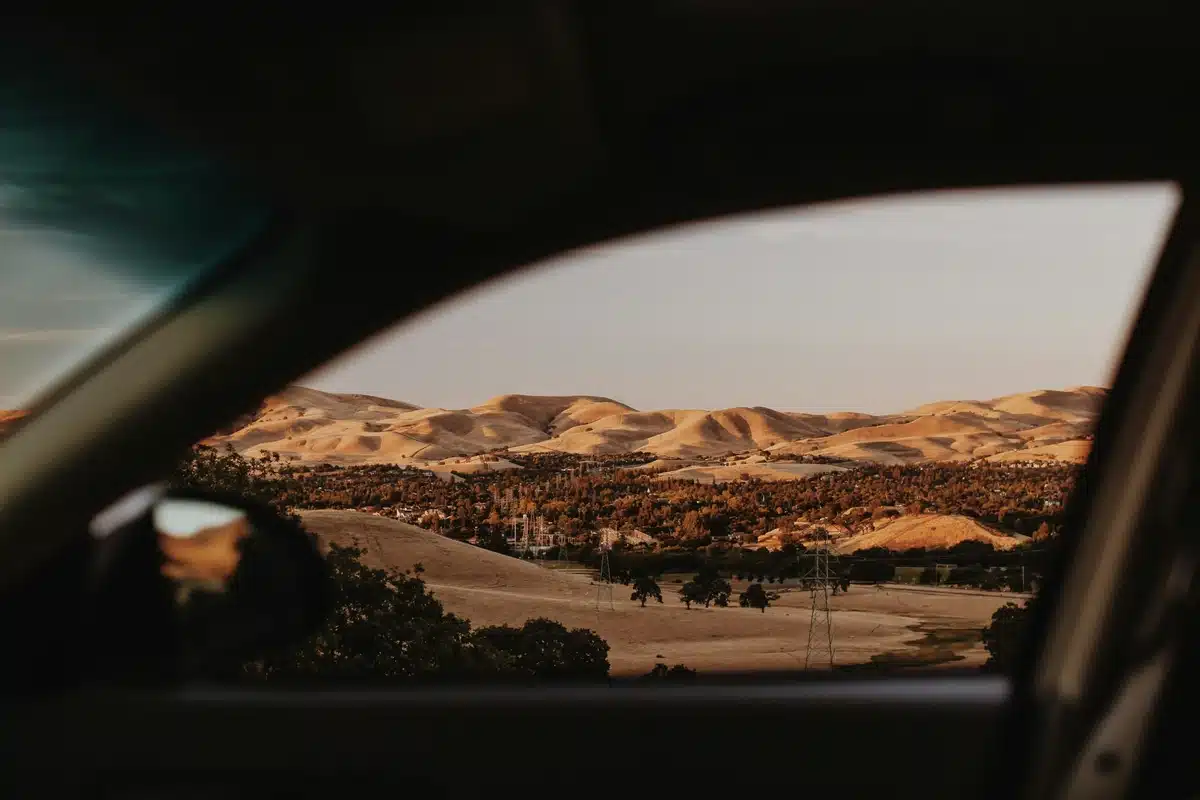 A view of the rolling desert hills in the Bay Area is photographed from a car window. Car detailing California makes beautiful views like this possible.