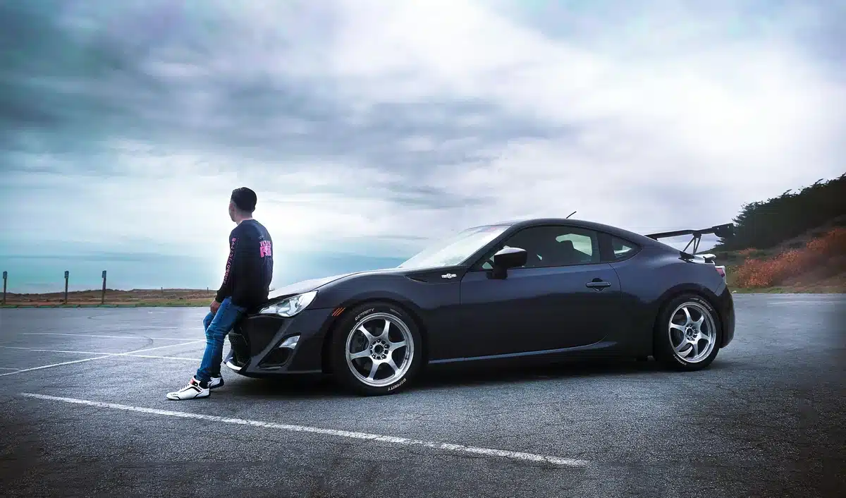 A young man is leaning in front of his JDM in California, along the coast in the Bay Area.