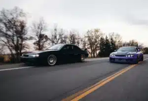 Two JDM cars driving along a road in California.