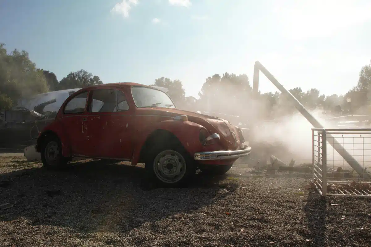 An orange vintage car is trashed in the sand after a San Francisco car break in.