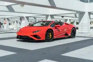 A bright red exotic car is parked in a geometric indoor parking garage.