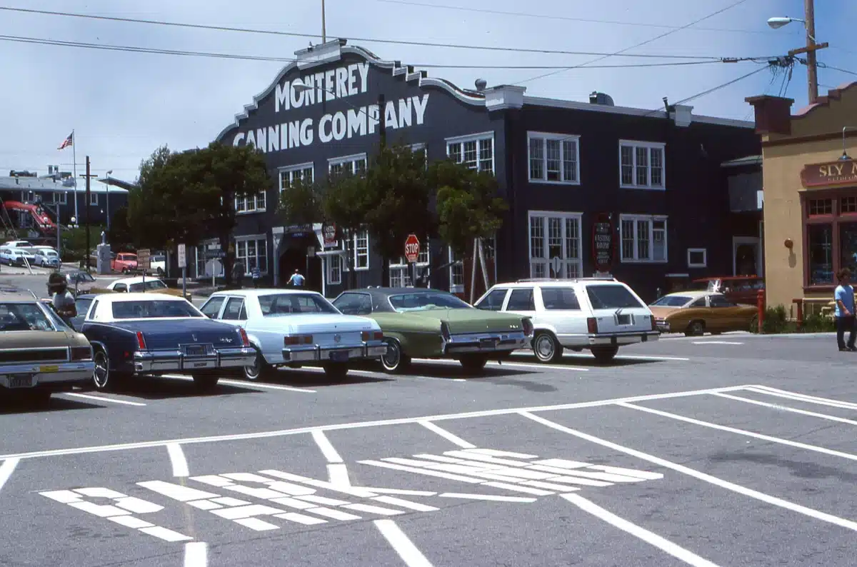 Some vintage cars are parking in a lot in front of a hotel at Monterey Car Week.