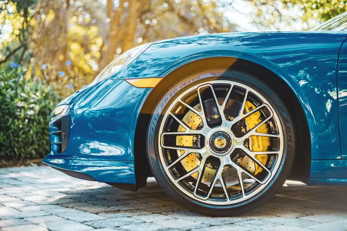 A close look at the front left corner of a blue sports car with ceramic coating or PPF, on a sunny day.