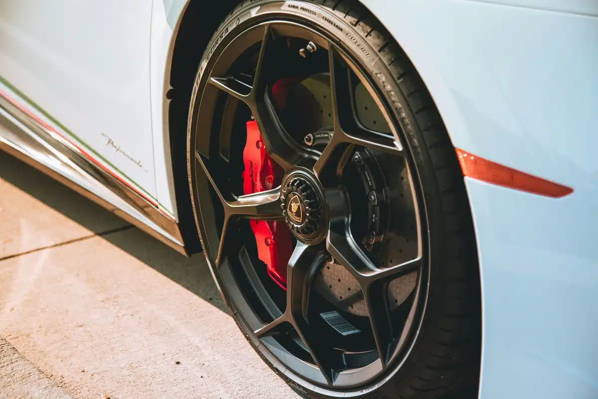 Red brake caliper paint is visible on a white sports car, pictured from the front right wheel.