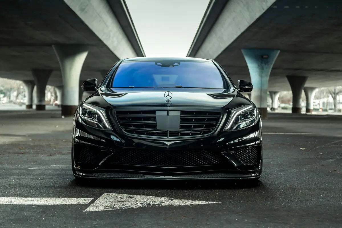 A black car, shining as if it was recently detailed, belowe an underpass in Livermore CA.