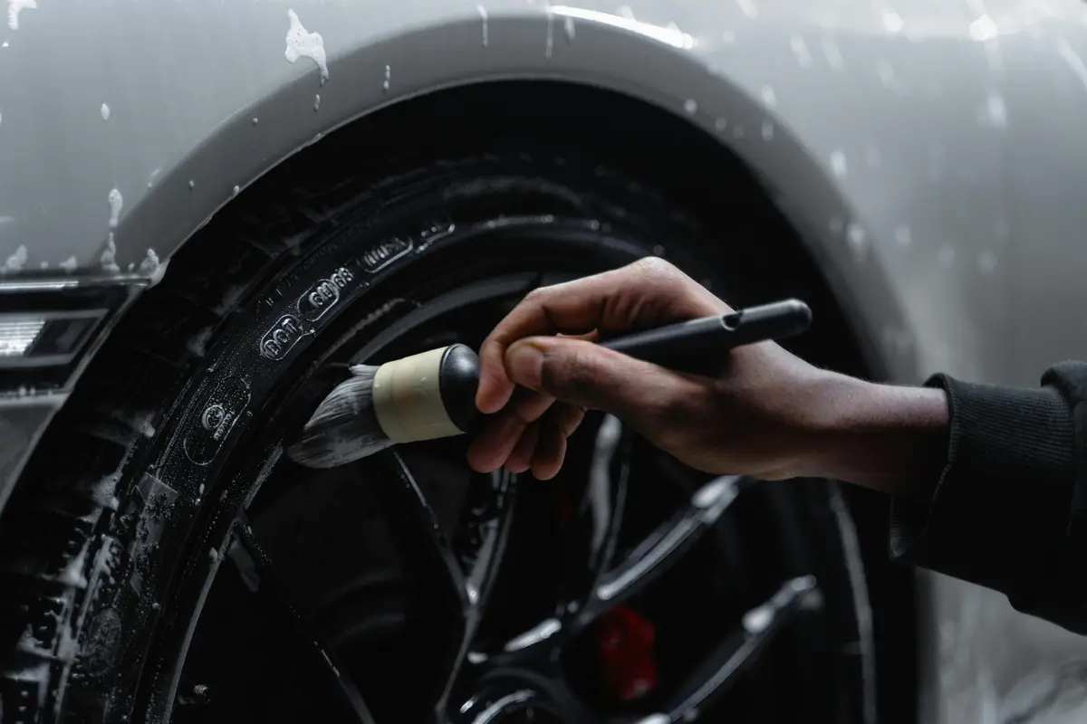 A close-up of someone's hand as they brush the inside of a car's tire, part of car detailing San Jose.