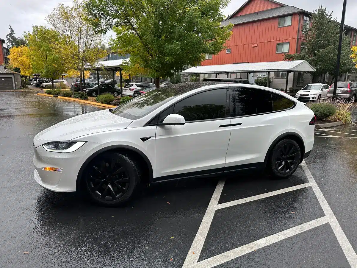 A white car with very dark tint, possibly 95 ceramic tint, on its windows.