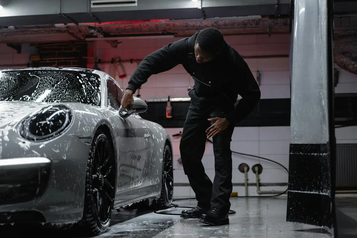 Someone is doing ceramic coating San Jose inside a garage on a white sports car.