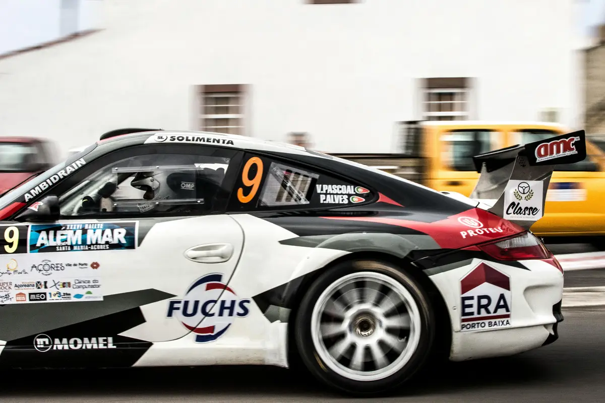 A white and black factory stock race car is pictured from the side. The front end is out of frame on the left.