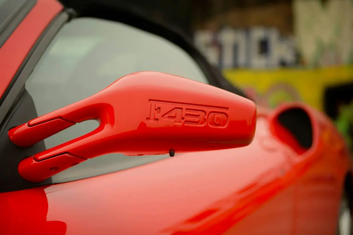 A rear view mirror on a classic red sports car after being detailed.