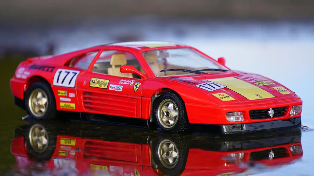 A red factory stock race car is parked on a shiny, reflective surface.