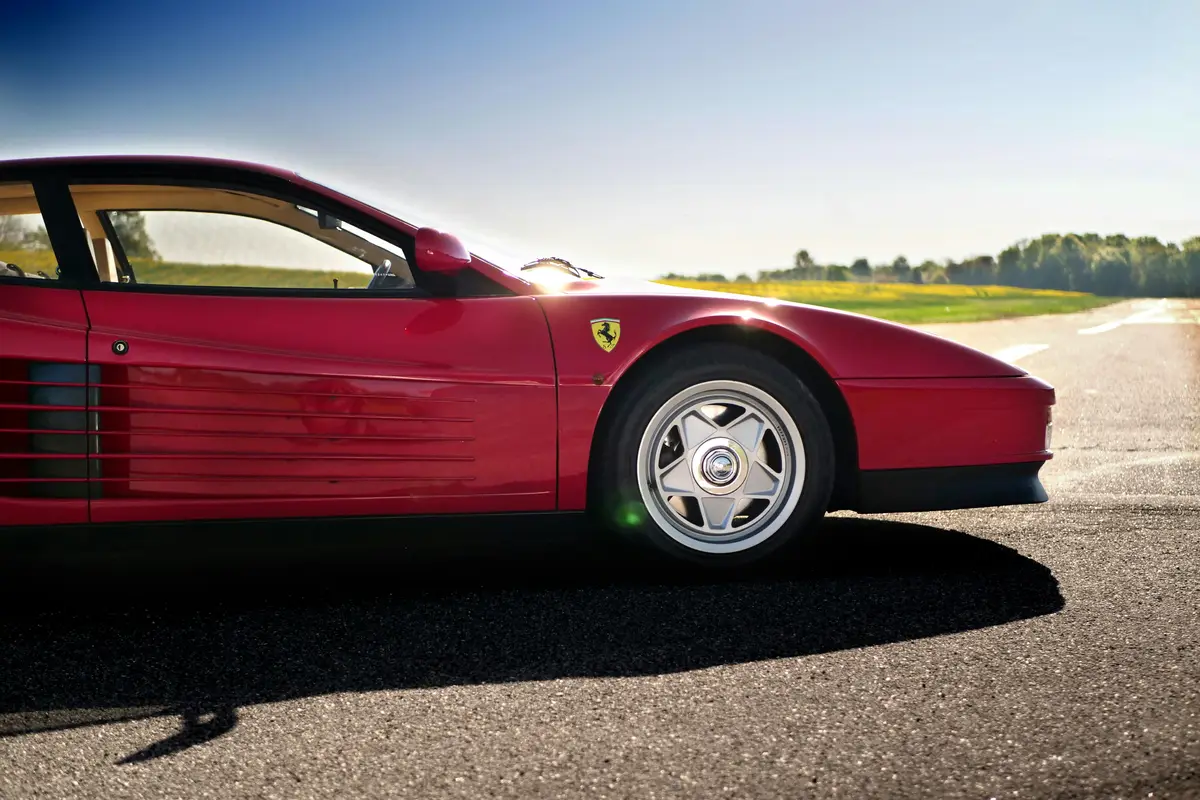 A red Ferrari photographed from the side, outside on a sunny day after getting ceramic coating San Jose.