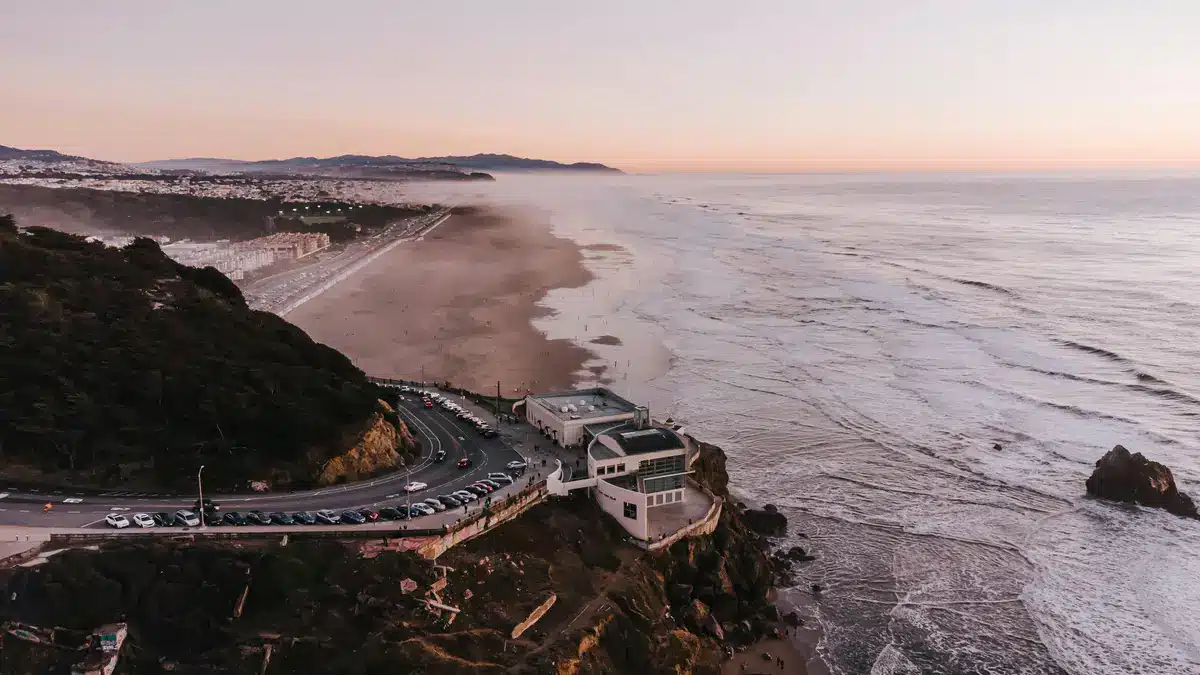 An overhead shot of a beach in Milpitas with a road and parking lot holding many cars.