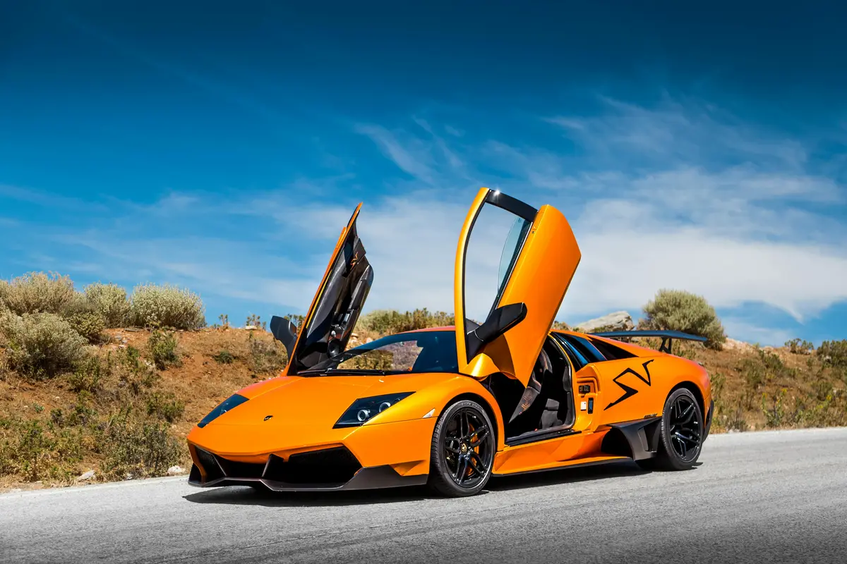 An orange luxury car is parked roadside in Milpitas CA with the doors open upwards, showing off the recently detailed body.