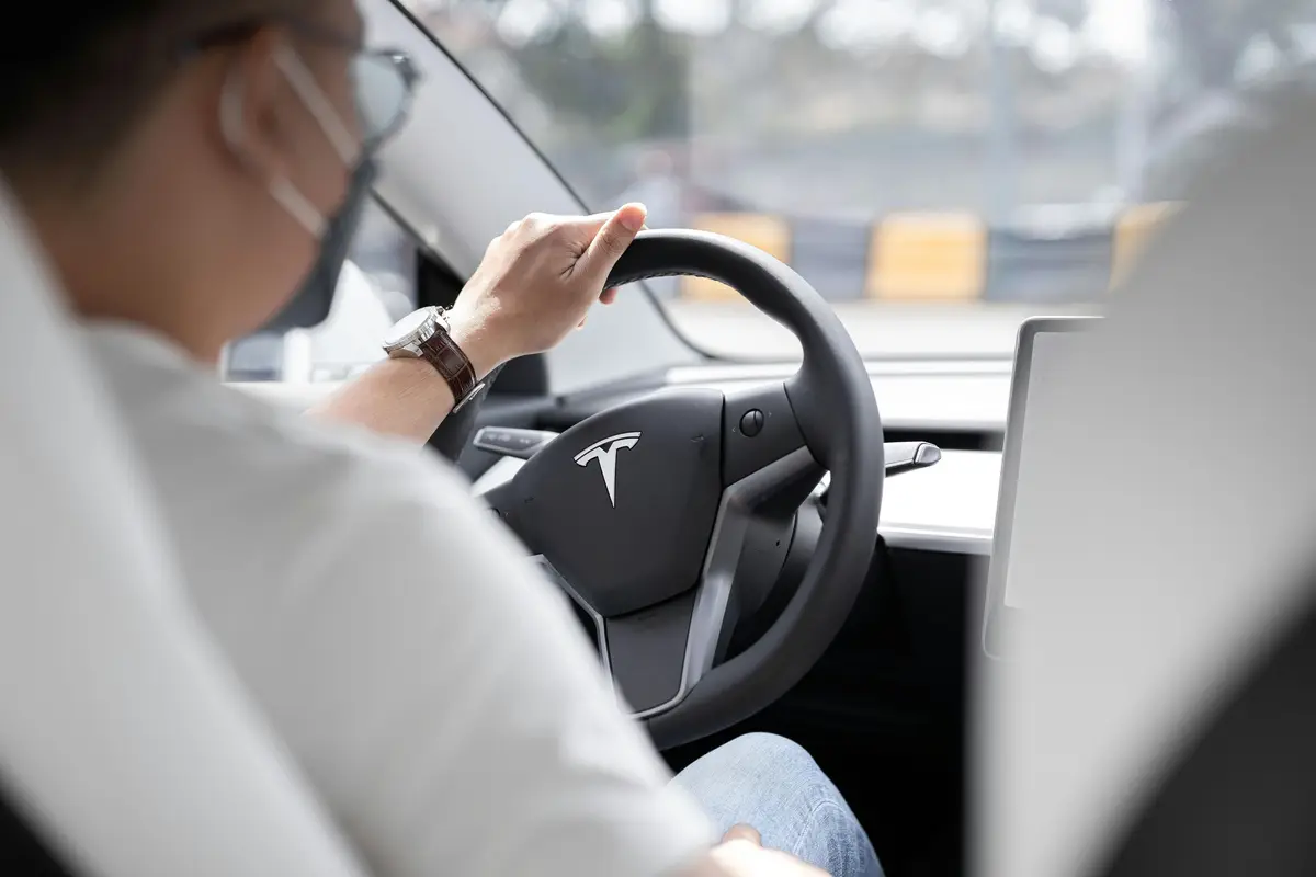 An over the shoulder shot of someone driving a Tesla.