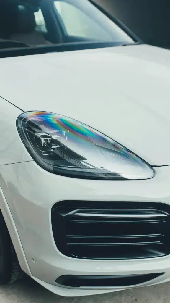 A front headlight on a white Porsche Cayenne