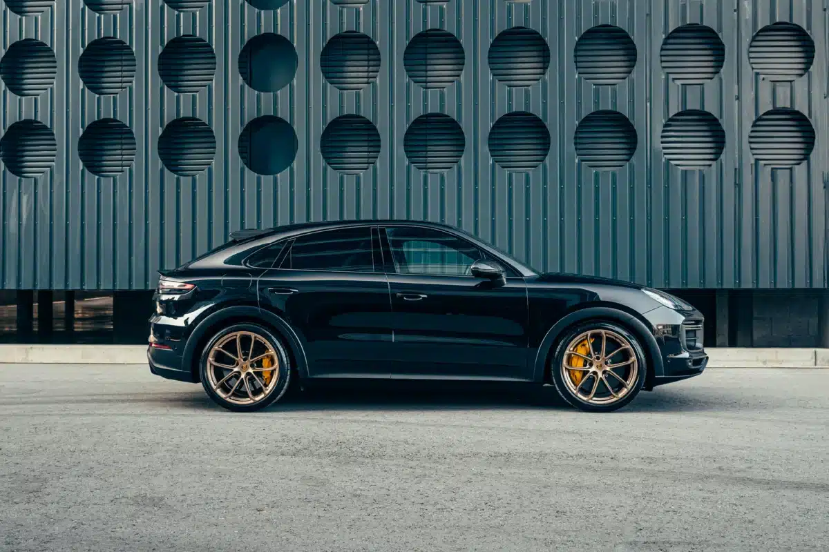 A Porsche Cayenne PPF job being shown off outside a blue building on a parking lot.
