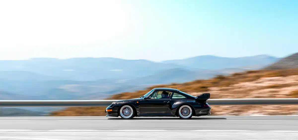 A black Porsche 911 is protected from the UV with PPF as it drives along a highway near Fremont California.