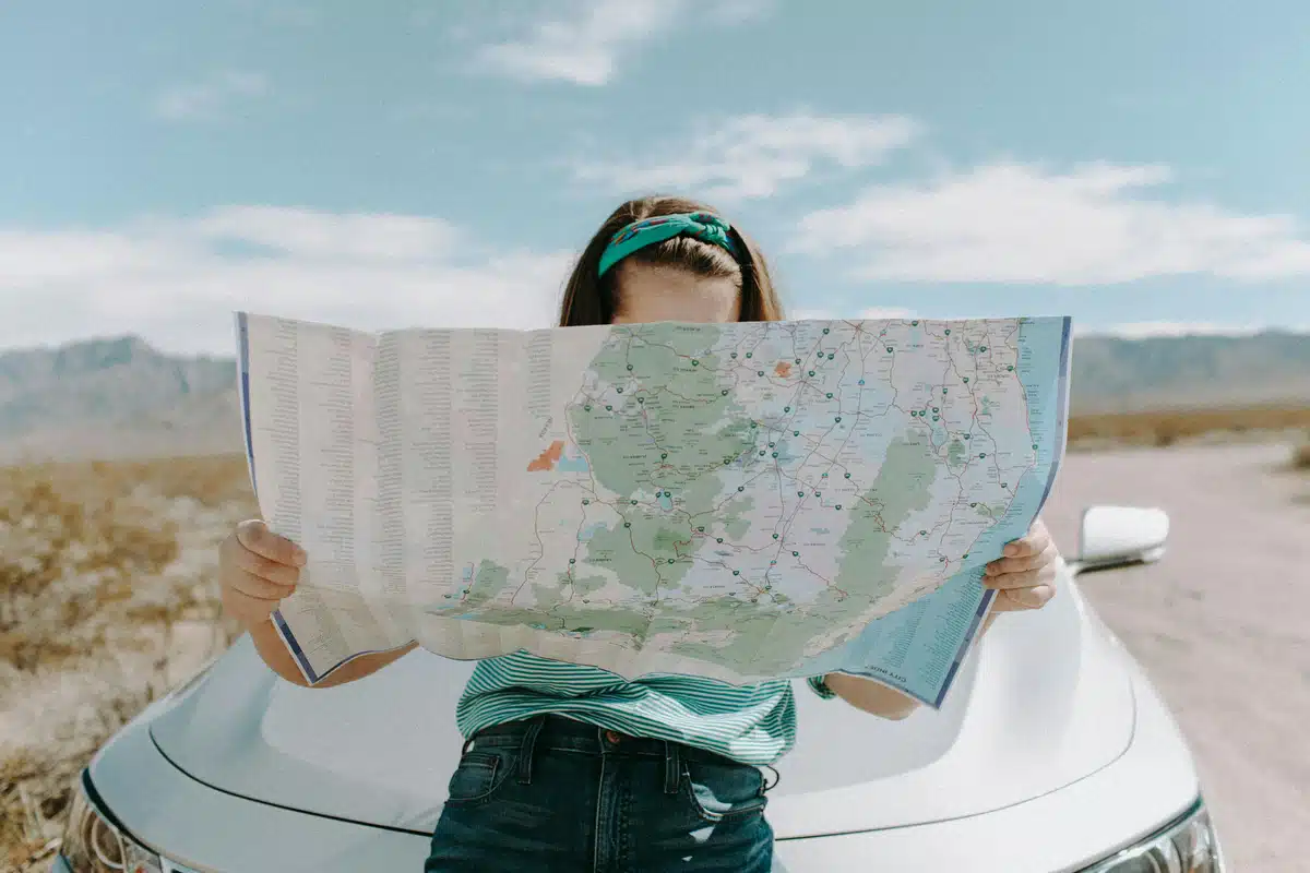 A driver is reading a map in front of her parked car on a highway in San Ramon CA. She's looking for Carzwerk's window tinting specialists.