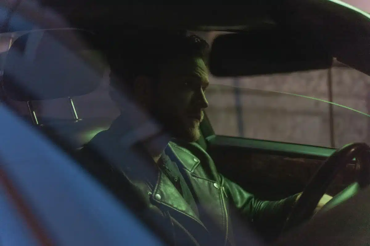A driver in the passenger's seat of a luxury car with window tinting driving through San Leandro.