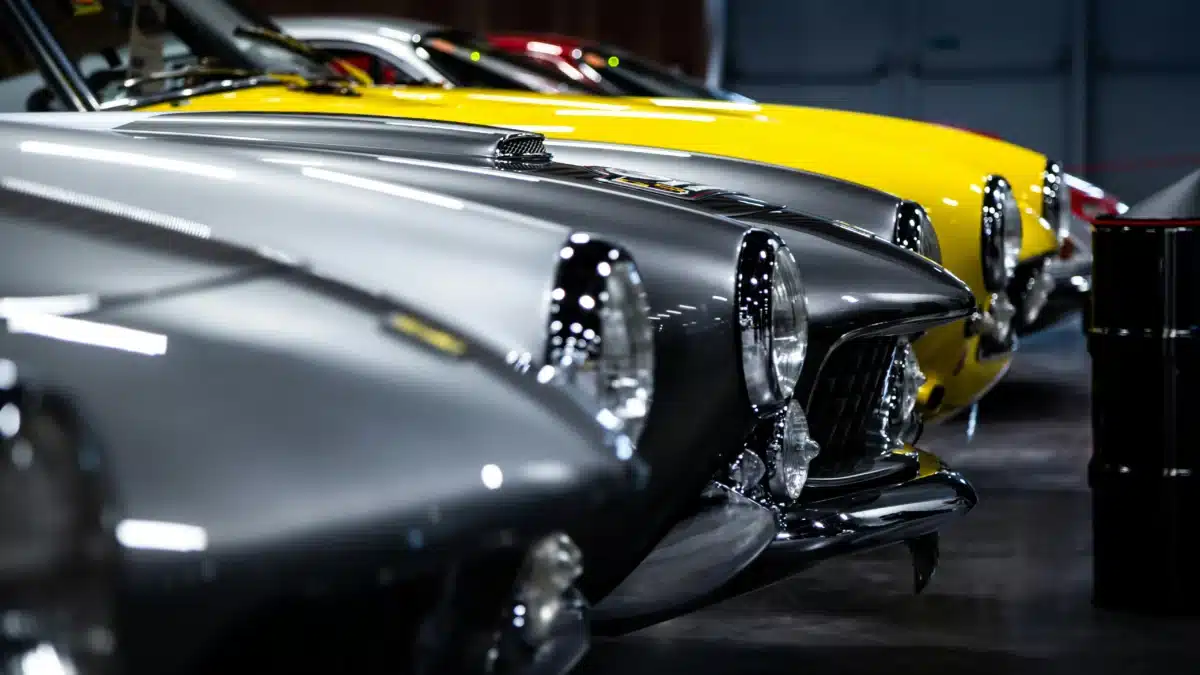 The front end of various Porsche models as they're parked side by side in a row, pictured from a side angle. 