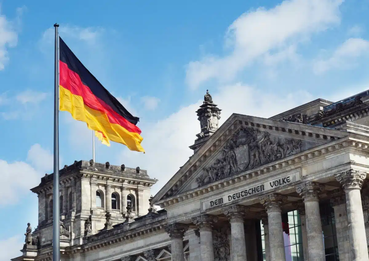 A German flag is flying over an old building on a sunny day. 
